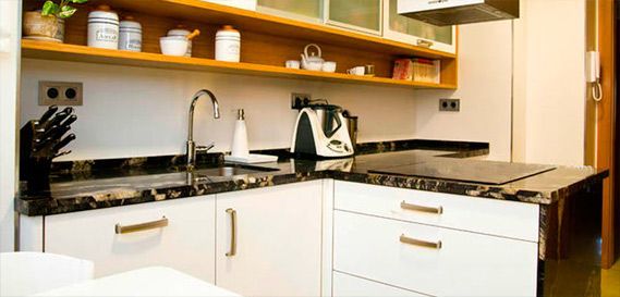 Una cocina con gabinetes blancos y una encimera negra.