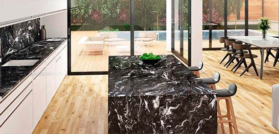 Una cocina con una gran encimera de mármol negro y taburetes.