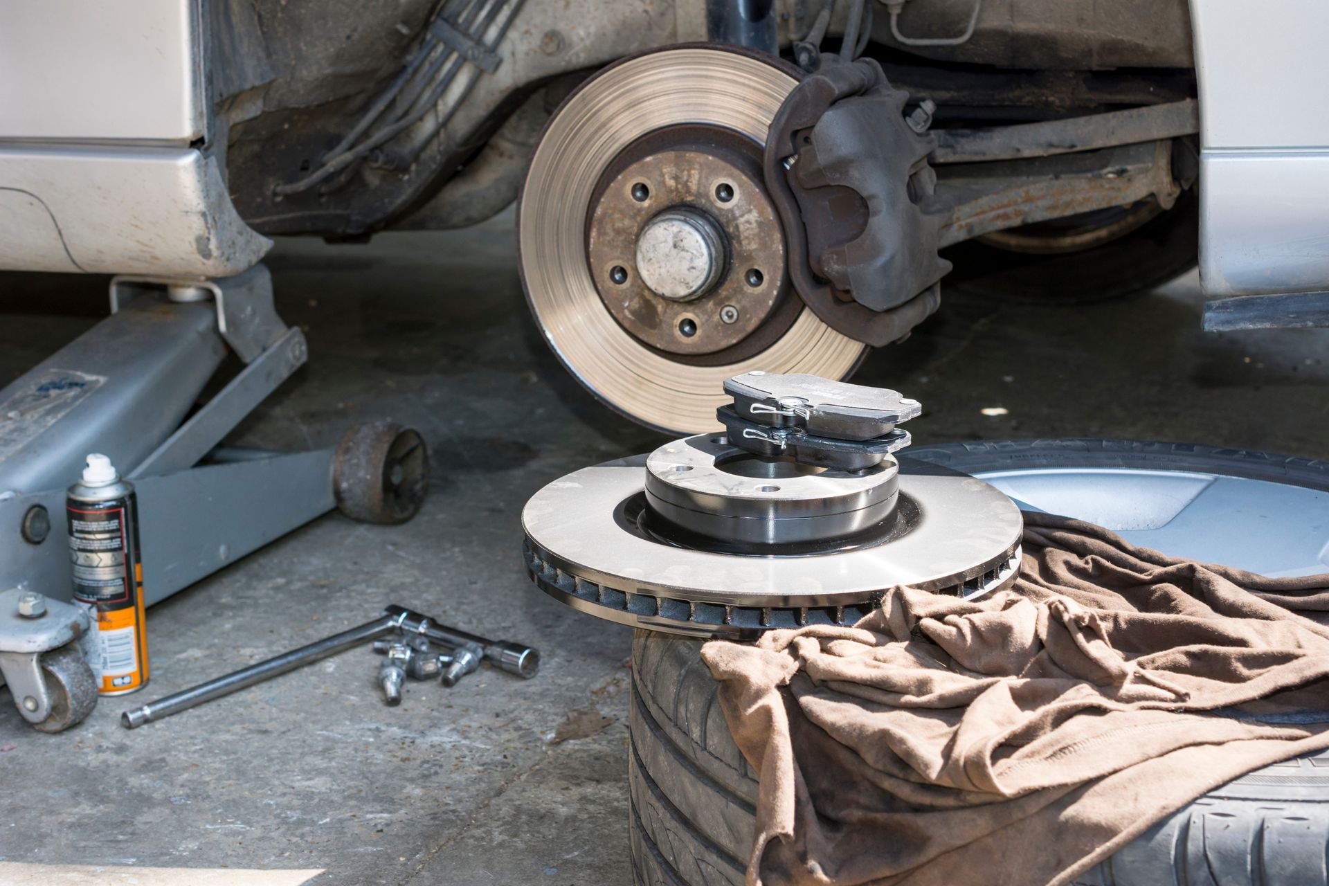 Remplacement des disques de frein d'une voiture à l'aide d'outils et d'un cric dans un garage.