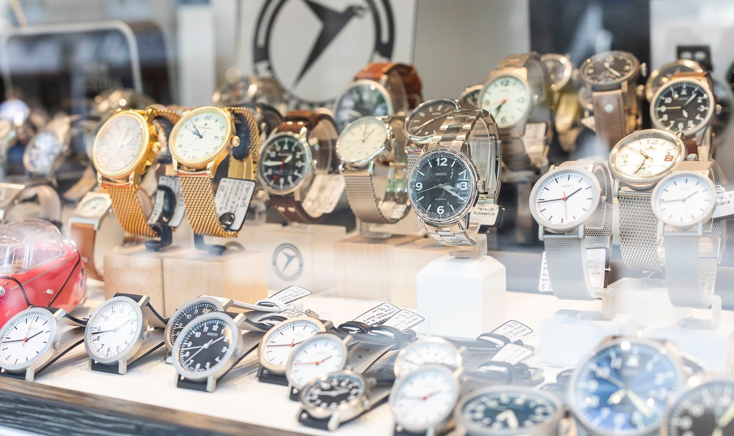 In einer Glasvitrine ausgestellte Uhren, verschiedene Stile und Farben, einige mit Metallbändern.