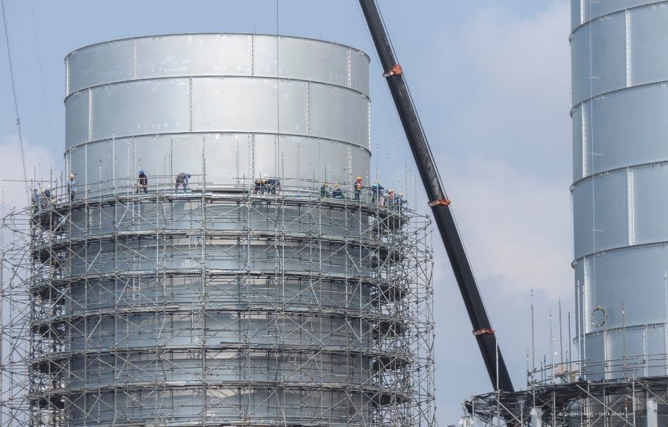 Draußen gestapelte Flüssigkeitstanks, Metallgestelle auf Paletten, bedeckter Himmel.