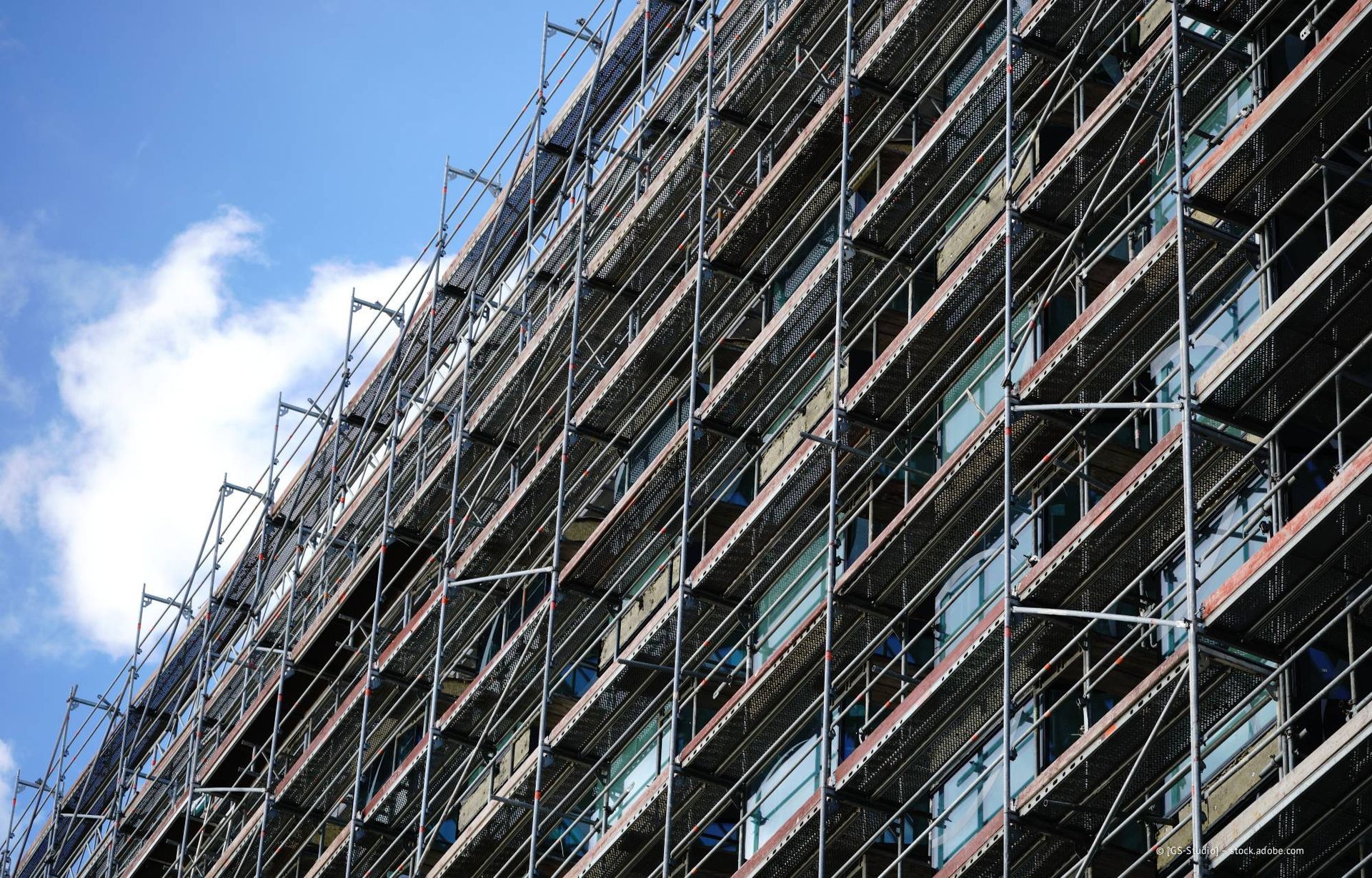 Ein im Bau befindliches Gebäude mit Baugerüst vor blauem Himmel.