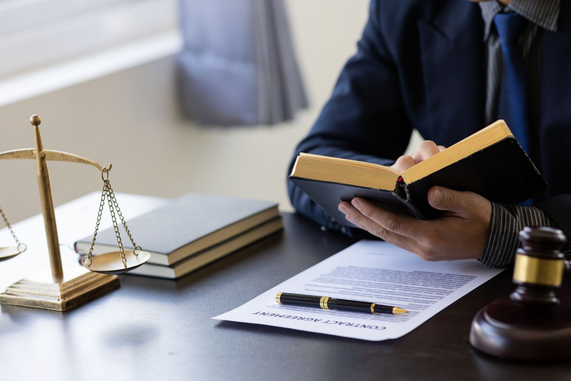 Un hombre está sentado en un escritorio leyendo un libro.