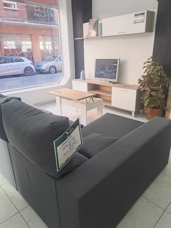 Una sala de estar con sofá, mesa y televisión.