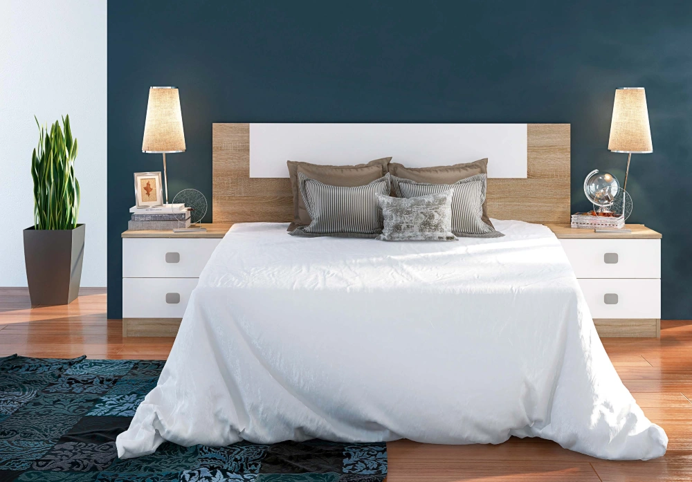 Un dormitorio con una cama, mesitas de noche, lámparas y una planta.