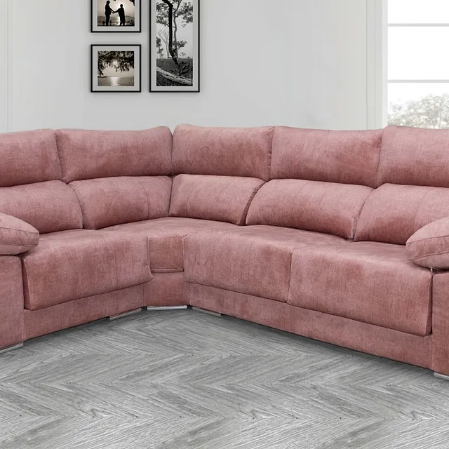 Un sofá seccional de color rosa está sentado sobre un piso de madera en una sala de estar.