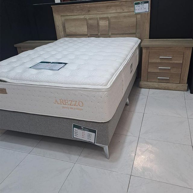 Una cama con un colchón blanco y un cabecero de madera.