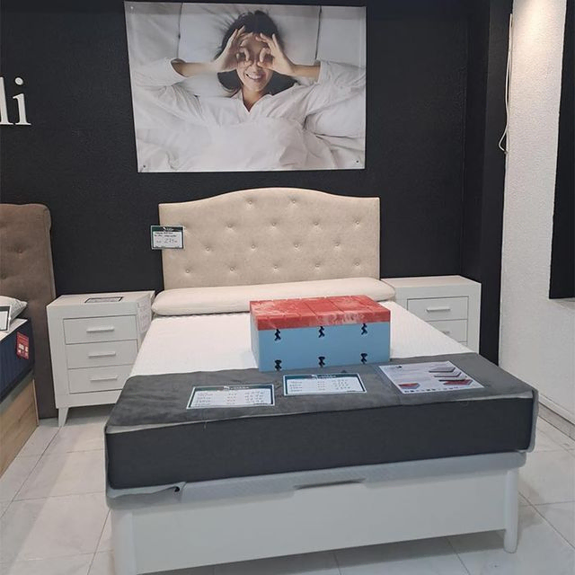 Una cama con una foto de una mujer en la pared encima.