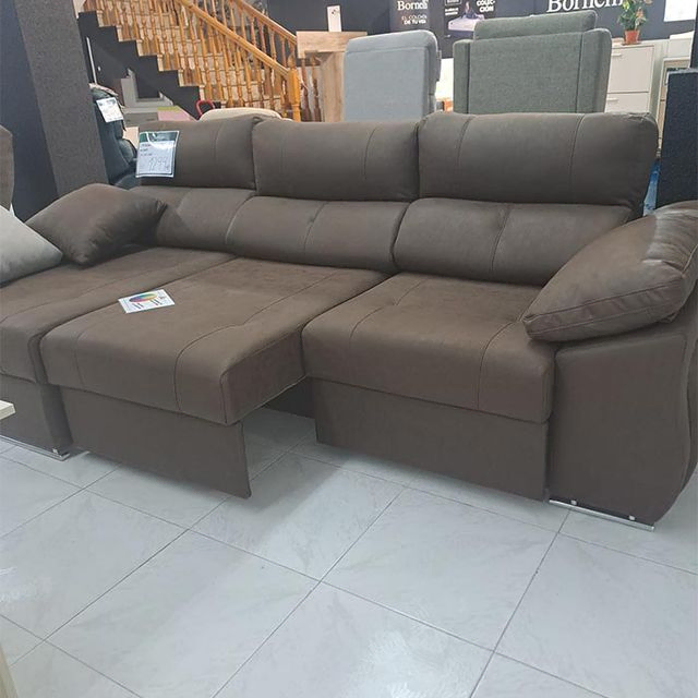 Un sofá marrón está sentado sobre un piso de baldosas en una sala de estar.