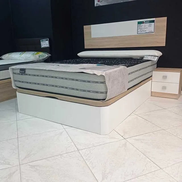 Una cama con un colchón y una mesita de noche en un dormitorio.