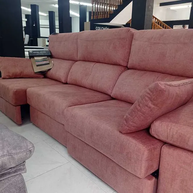 Un sofá rosa está en una habitación con escaleras al fondo.