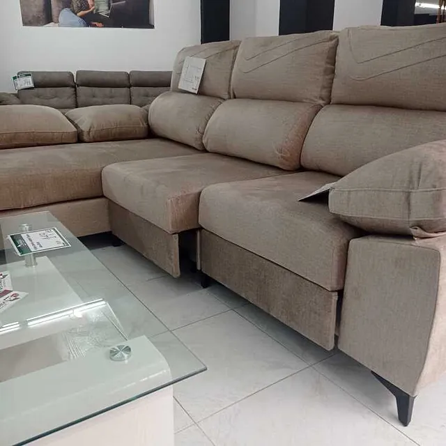 Una sala de estar con un gran sofá seccional y una mesa de café de vidrio.