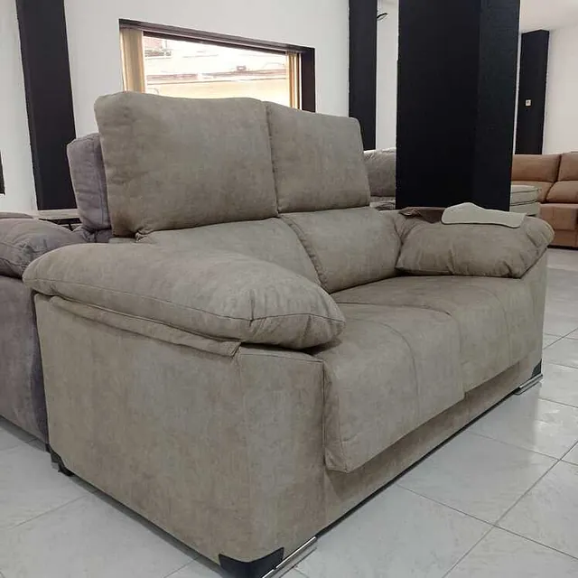 Un sofá beige está sentado sobre un piso de baldosas en una sala de estar.