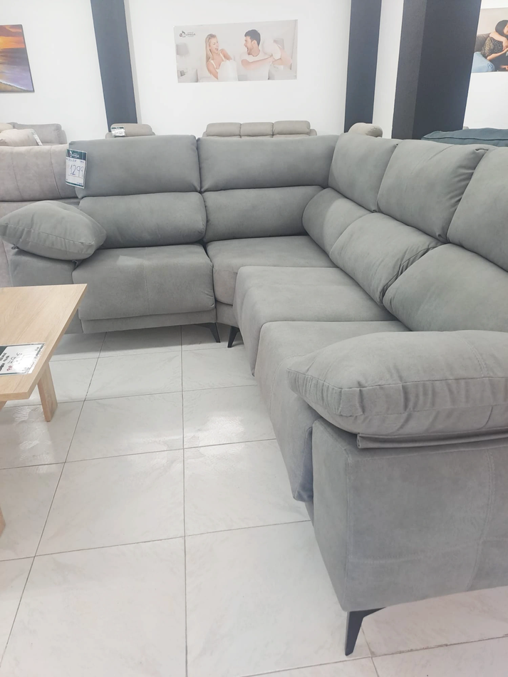 Un sofá seccional gris está ubicado en una sala de estar junto a una mesa de café.