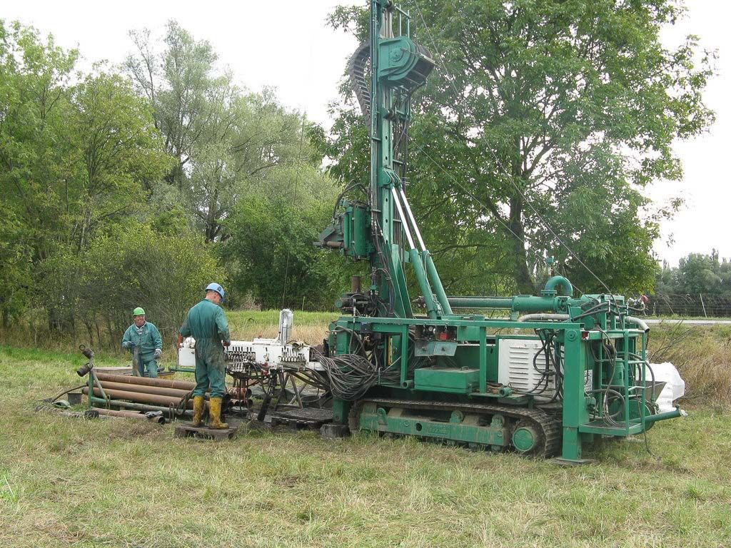 Ein Mann steht neben einer grünen Maschine auf einem Feld - IBOTECH Bohr- und Brunnenbau GmbH aus Zöberitz bei Landsberg