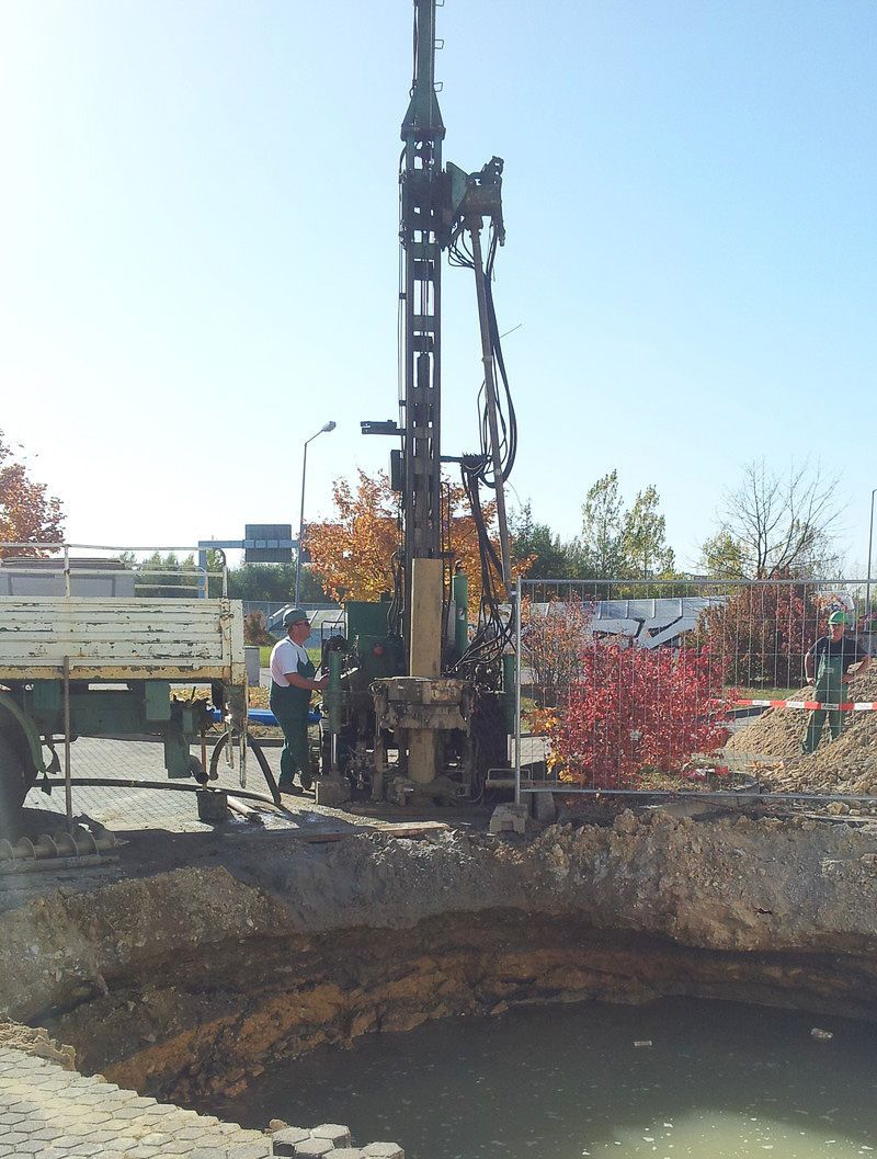 Ein Mann steht neben einer großen Maschine in einem Erdloch - IBOTECH Bohr- und Brunnenbau GmbH aus Zöberitz bei Landsberg