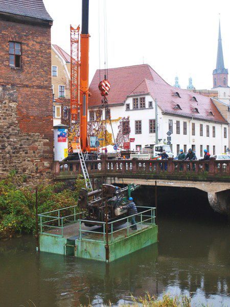 Ein Kran hebt ein Fahrzeug über eine Brücke über einen Fluss - IBOTECH Bohr- und Brunnenbau GmbH aus Zöberitz bei Landsberg
