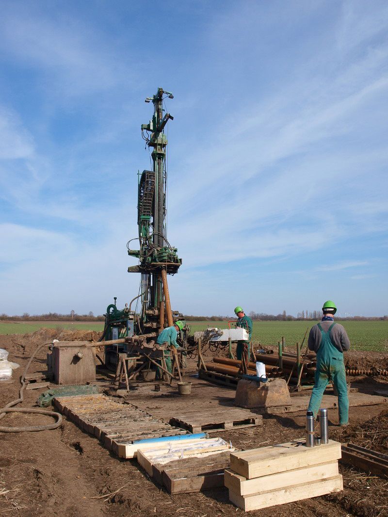 Ein Mann steht vor einer großen Maschine auf einem Feld - IBOTECH Bohr- und Brunnenbau GmbH aus Zöberitz bei Landsberg