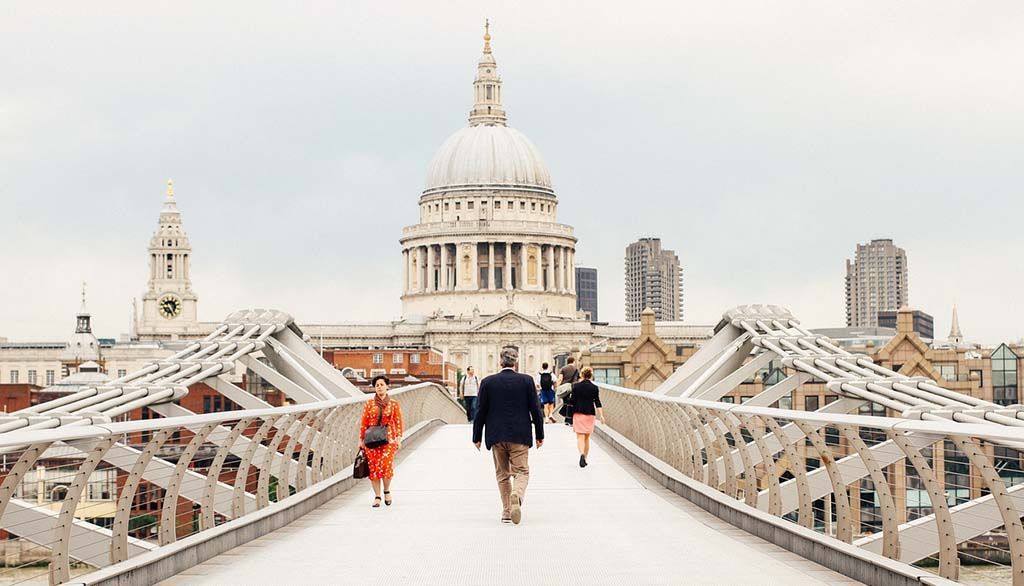 Des passants empruntent le Millennium Bridge en direction de la cathédrale Saint-Paul à Londres par temps couvert.