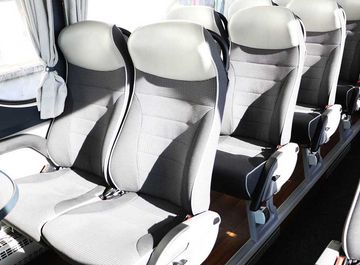 Des sièges d'autocar gris et blancs vides, disposés en rangées à l'intérieur du véhicule.