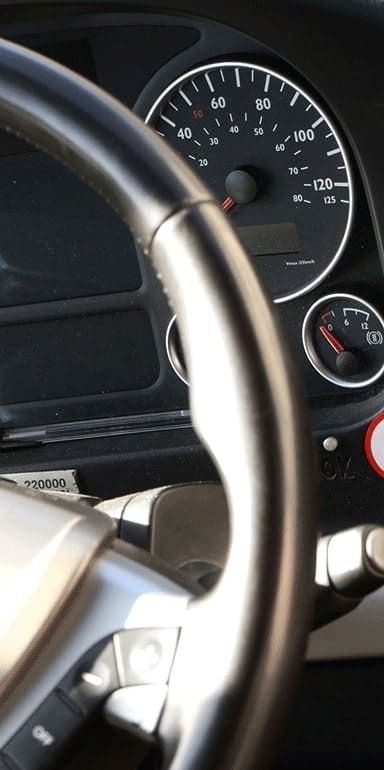 Gros plan sur le volant et le tableau de bord d'un véhicule, montrant le compteur de vitesse et la jauge à carburant.