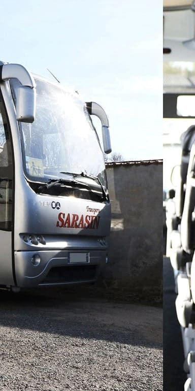 Un bus touristique argenté avec l'inscription SARASIN à l'avant, garé à l'extérieur sur un terrain gravillonné près d'un mur.