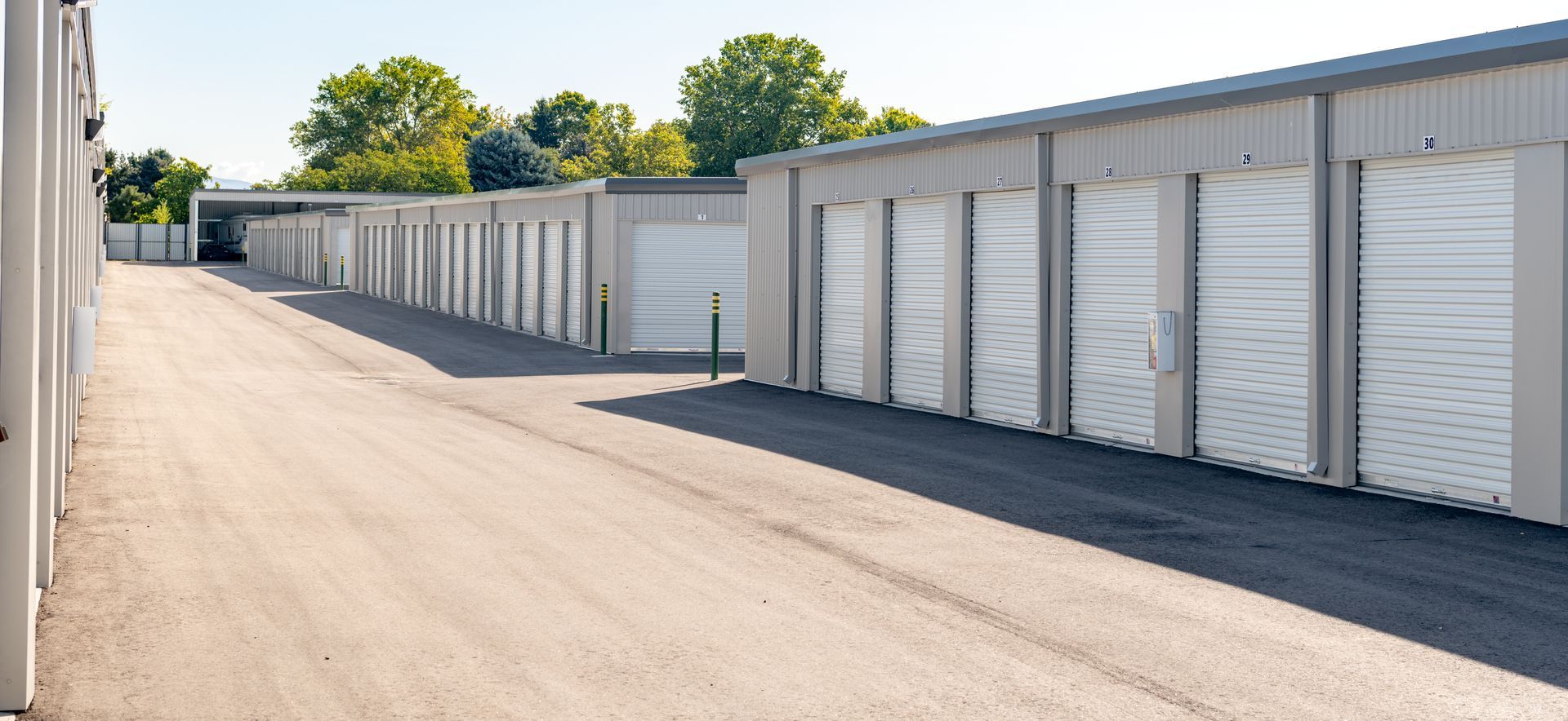 Rangée de garages blancs de type entrepôt le long d'une allée asphaltée