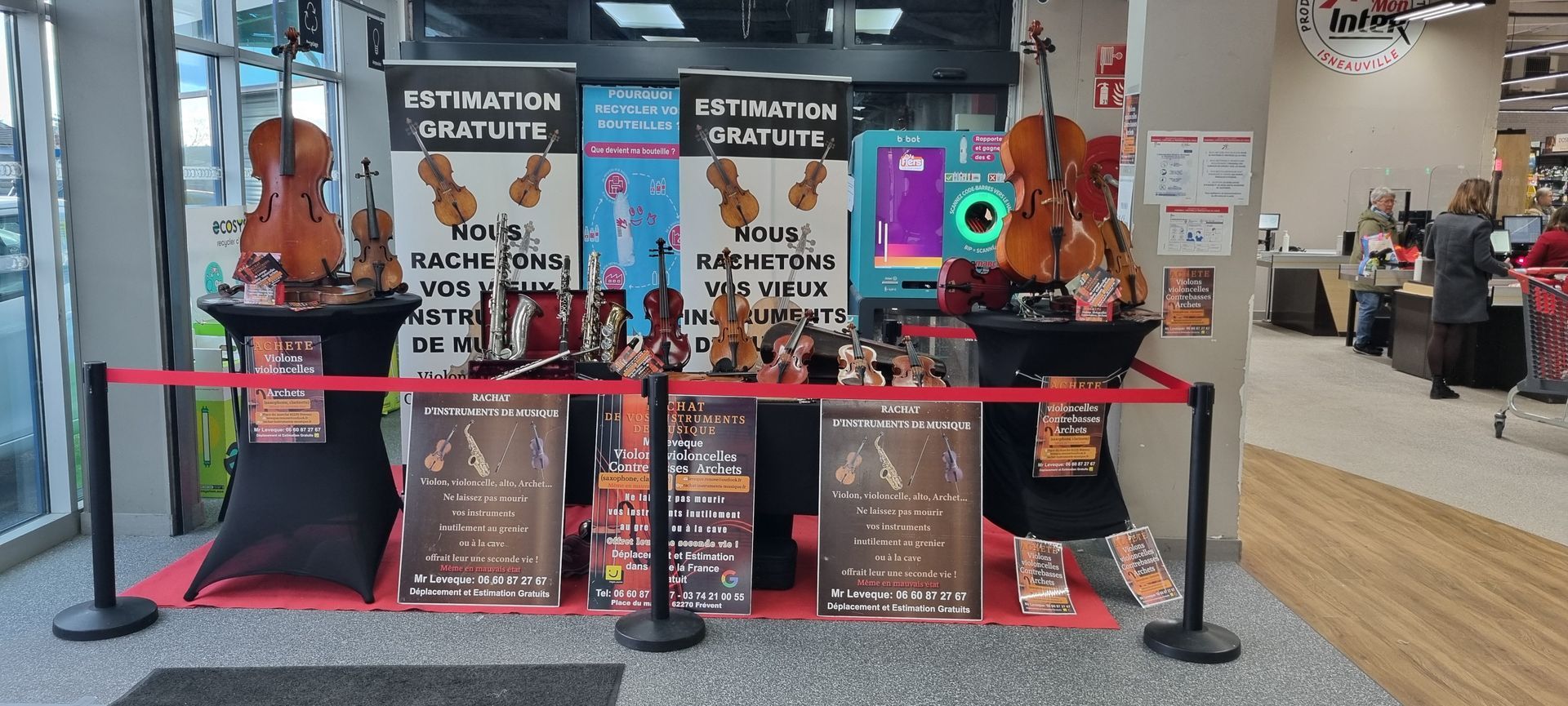 Présentation d'instruments de musique dans un magasin, avec des violons, des bannières et une corde de velours rouge.