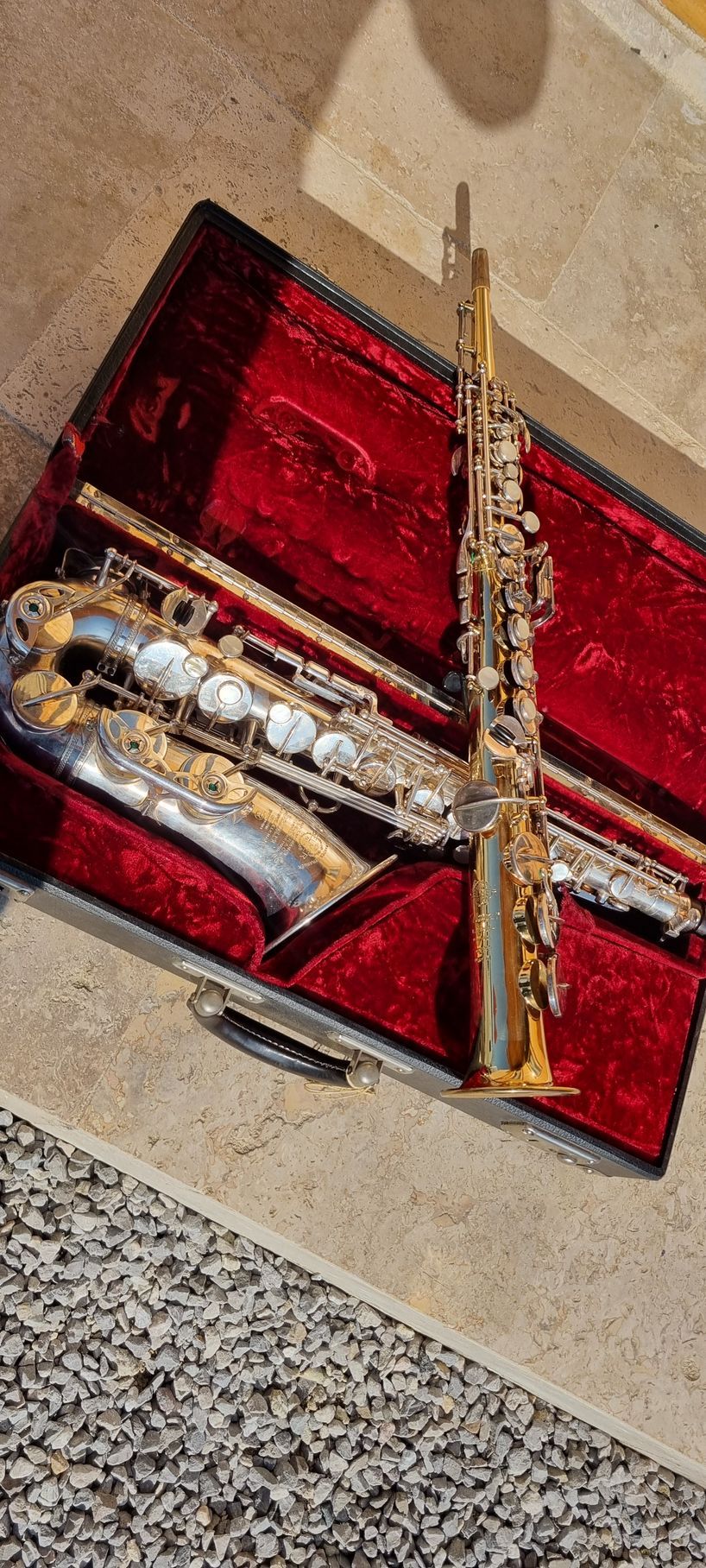 Un saxophone soprano et un saxophone alto dans un étui doublé de rouge.