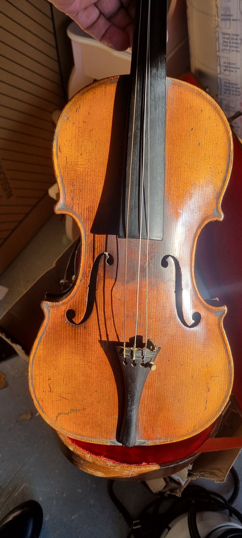 Un violon à la touche sombre, reposant dans son étui doublé de rouge.