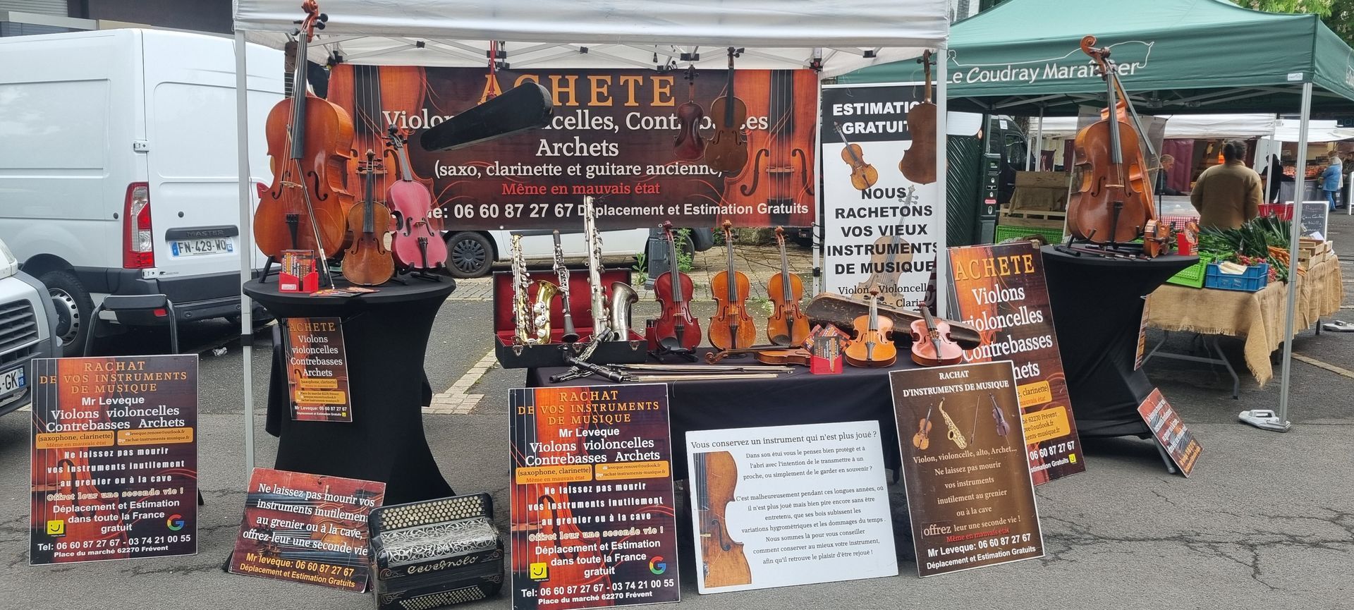 Un stand sur un marché expose des violons et des panneaux d'information.