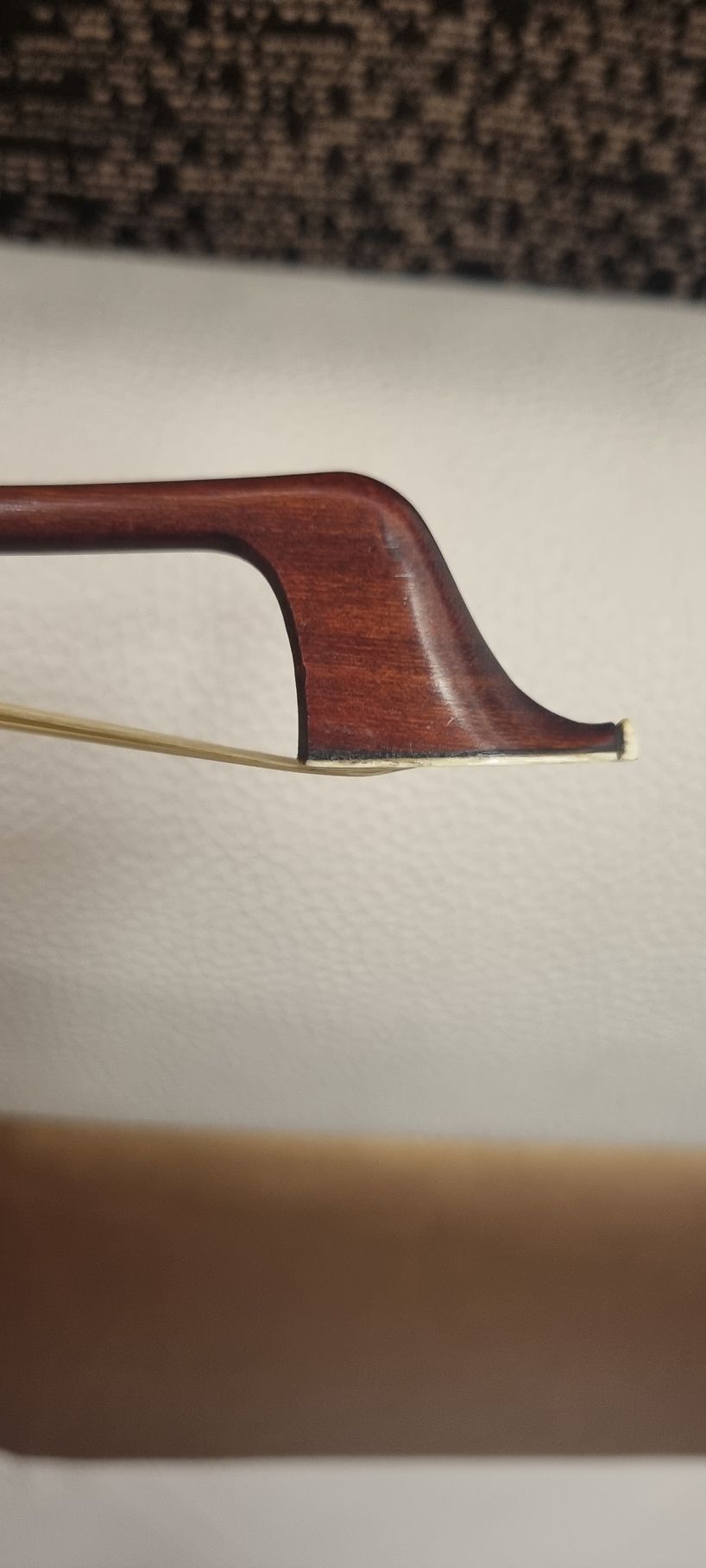 Gros plan sur la tête d'un archet de violon, montrant sa forme incurvée et sa matière en bois.