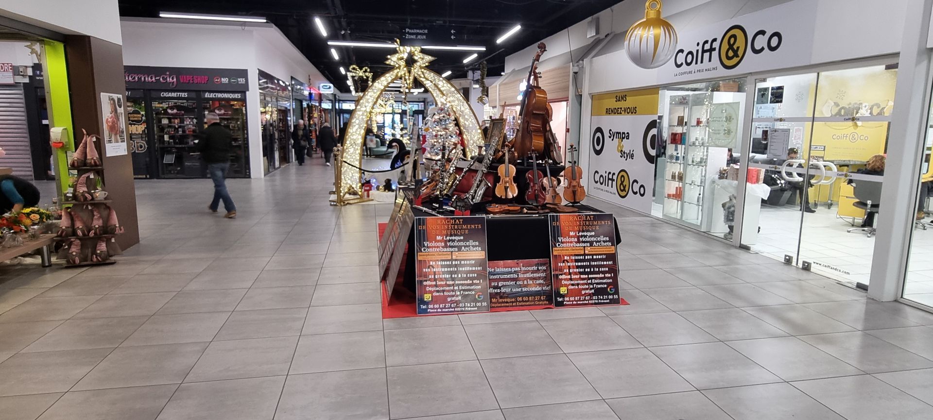 Intérieur d'un centre commercial. Table d'exposition avec des marchandises au centre. Boutiques et personnes en arrière-plan.