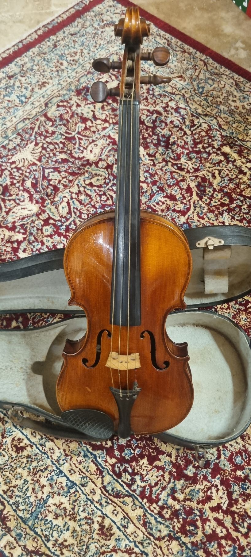 Violon posé sur un tapis à motifs, dans son étui ouvert.