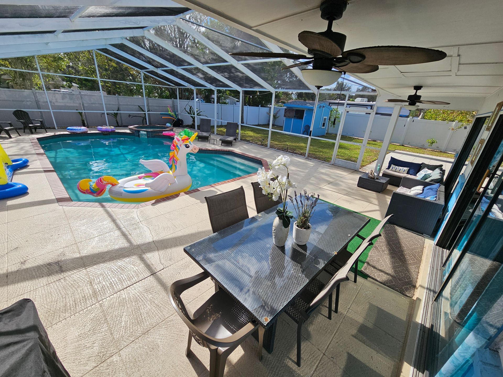 Pool and patio area with dining table, lounge furniture, and a unicorn float.