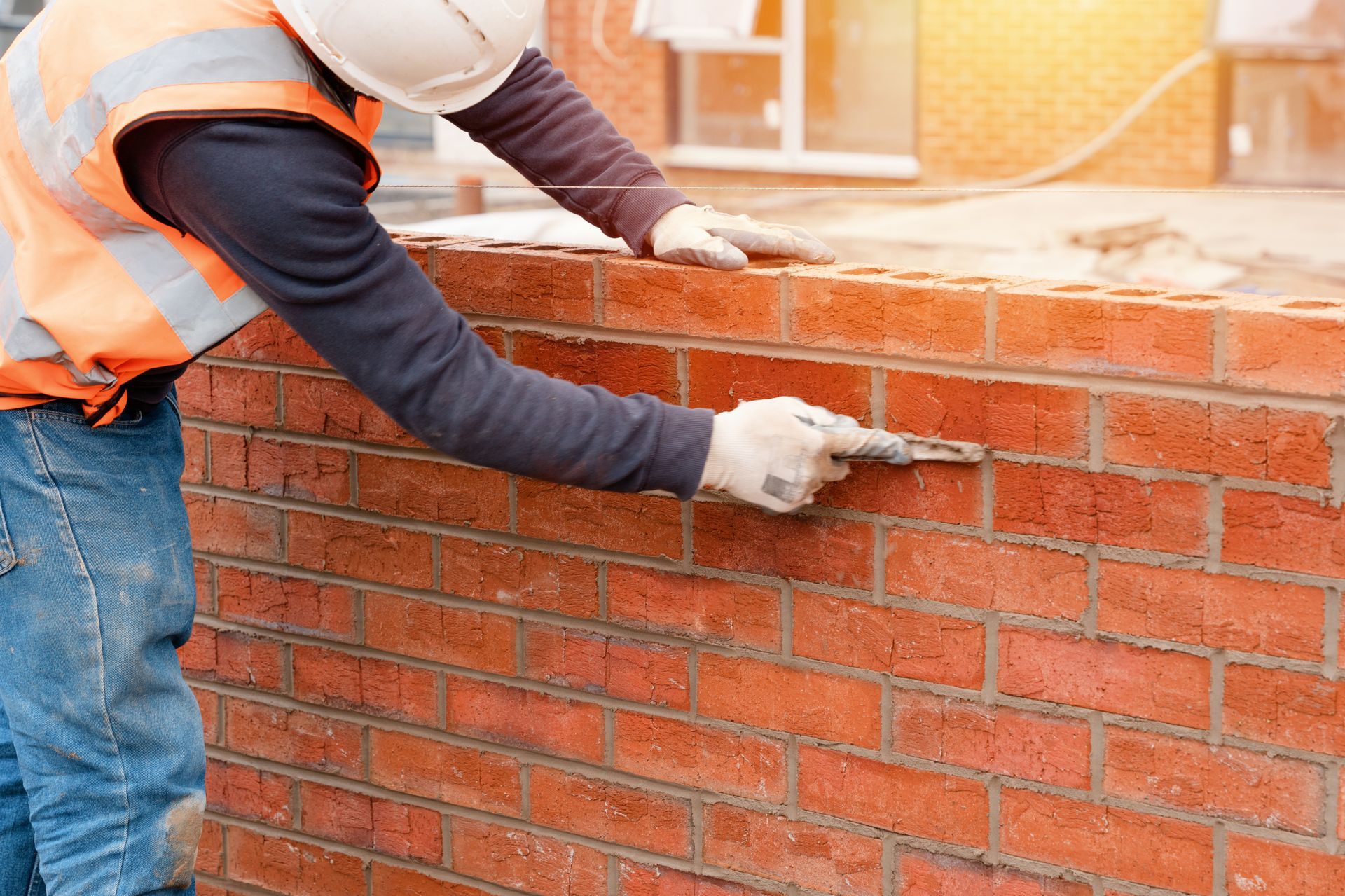 Ein Bauarbeiter legt Ziegelsteine ​​an eine Wand.