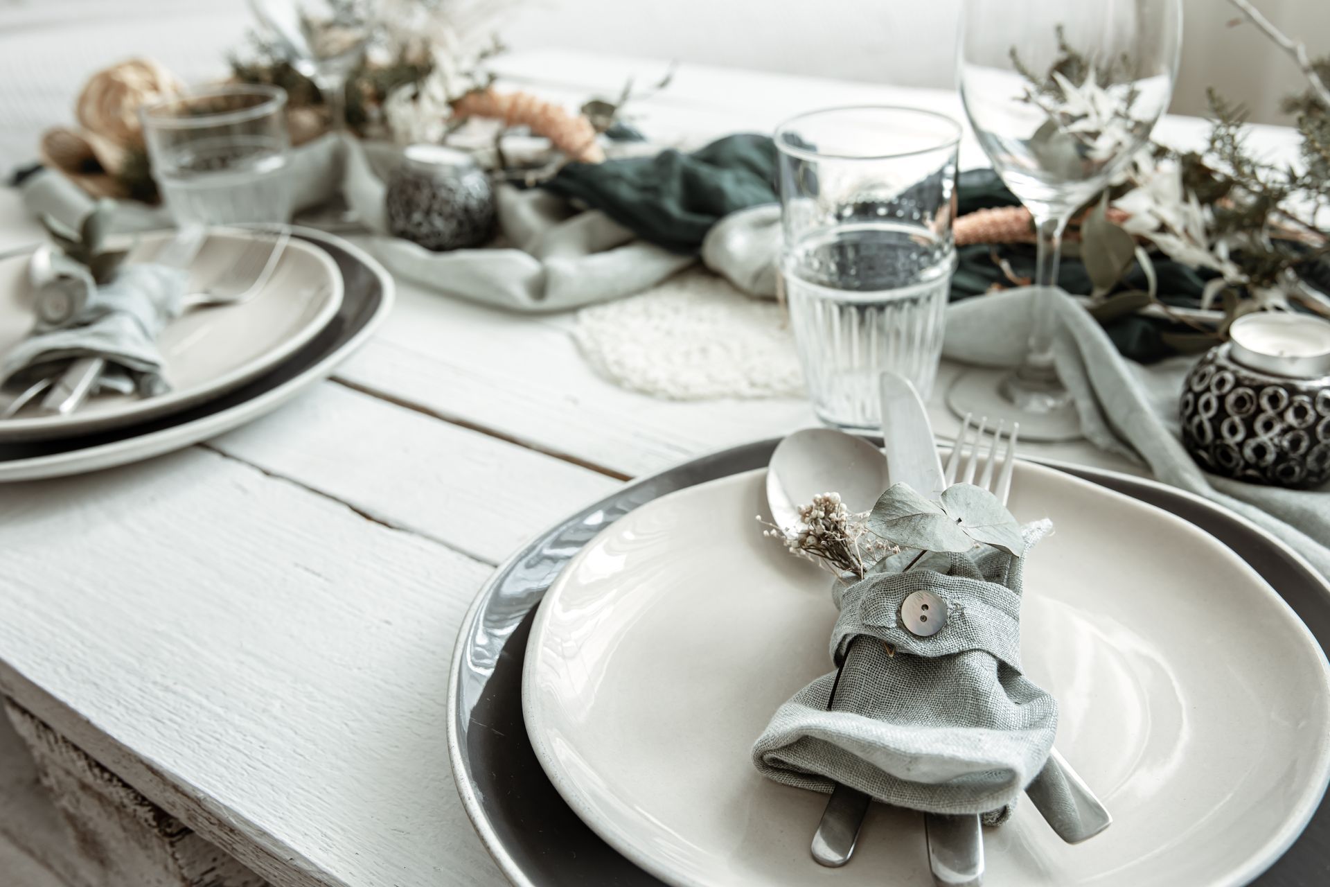 Tisch gedeckt mit Tellern, Besteck und Dekorationen.