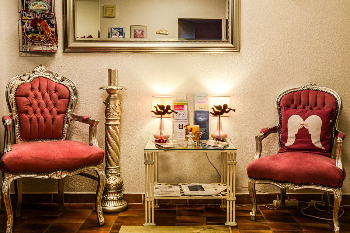 Ein Wartezimmer mit zwei roten Stühlen und einem Tisch