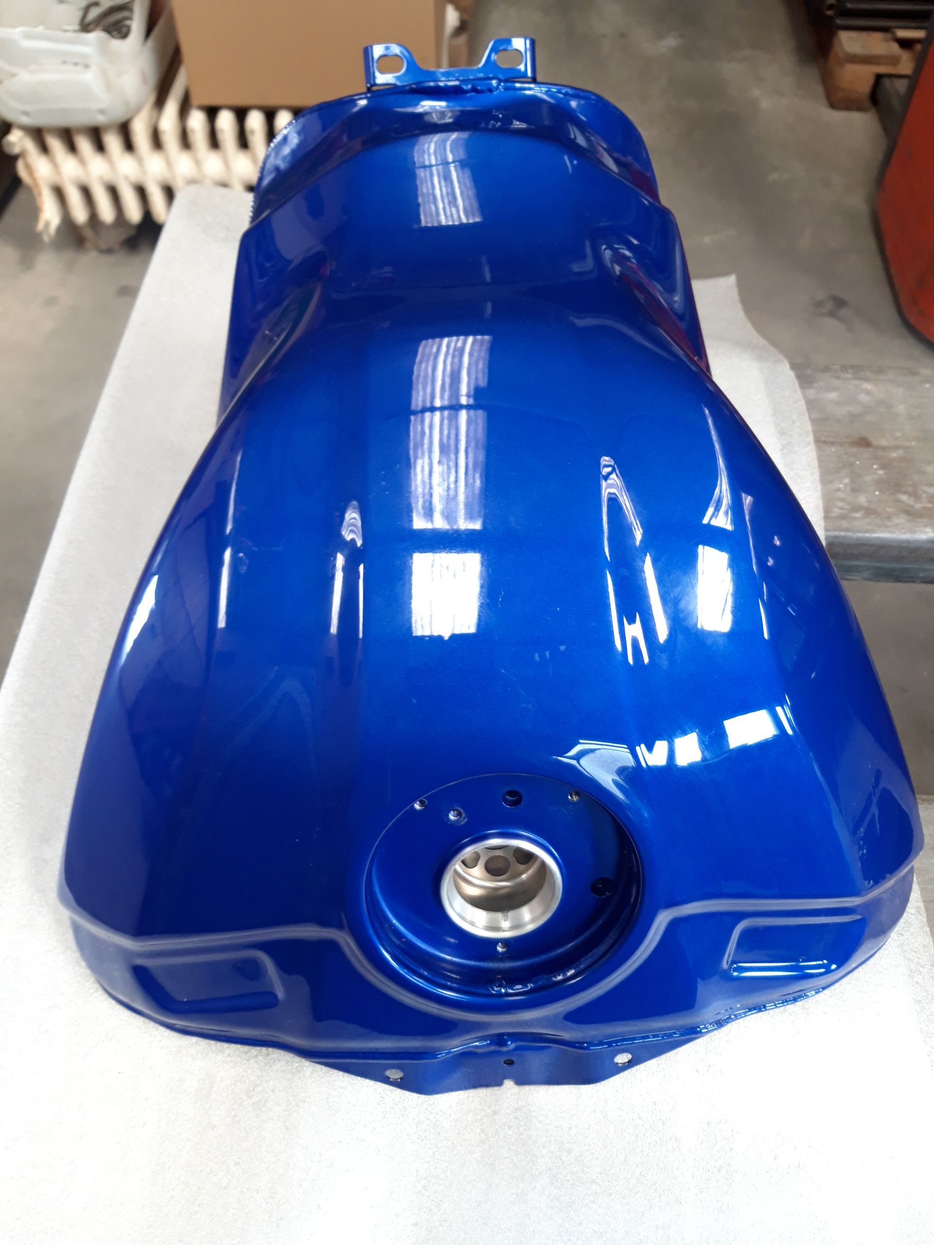 Réservoir d'essence bleu d'une moto que Berry Décap a dégraissé