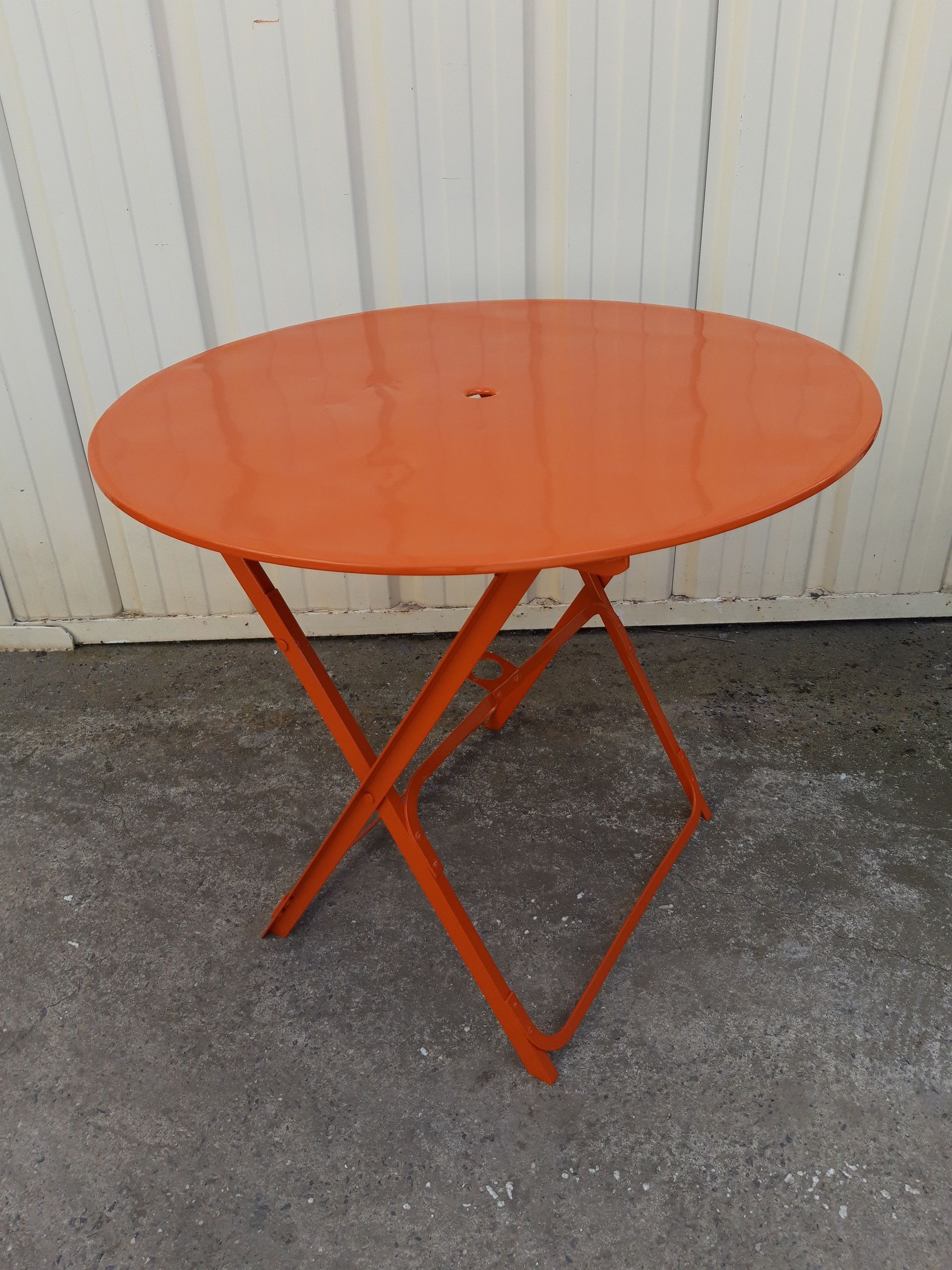 Exemple de thermolaquage sur une table de jardin orange en métal, après décapage