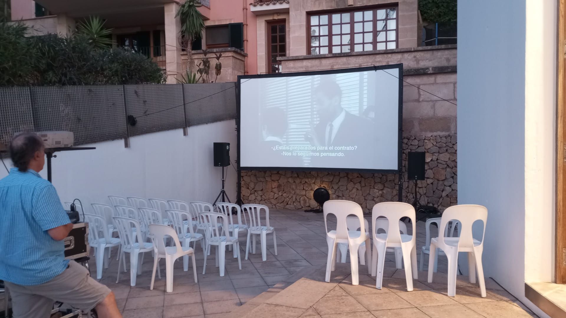 Un hombre está viendo una película en una pantalla grande frente a una fila de sillas.