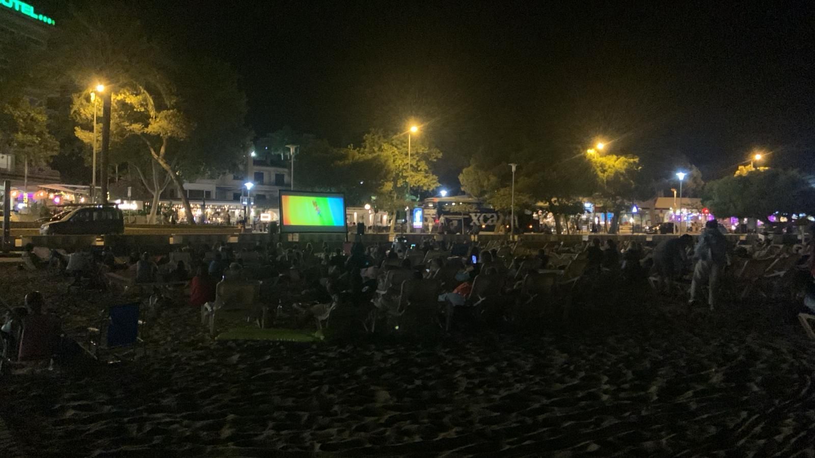 Una multitud de personas se reúne en un parque por la noche.