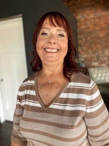 A woman in a striped shirt is smiling for the camera.