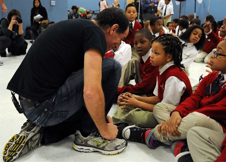 A man kneeling down with a group of children sitting on the floor