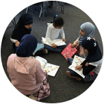 A group of children are sitting on the floor reading books.