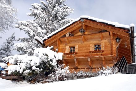 Une allée enneigée devant une grande maison en brique.