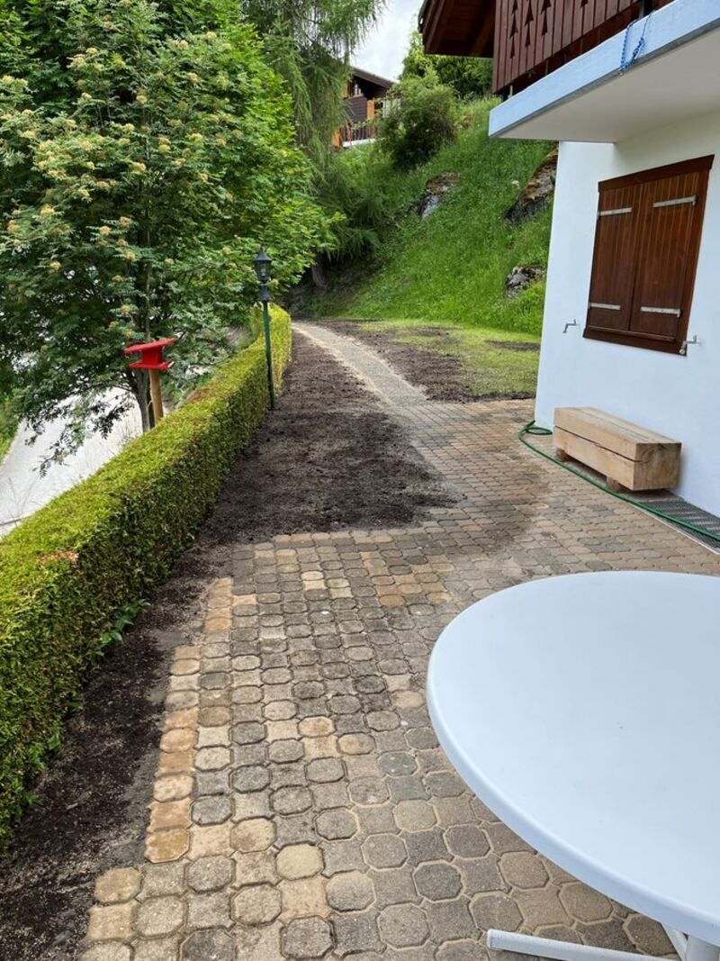 Une table blanche est posée sur un patio à côté d'une maison.