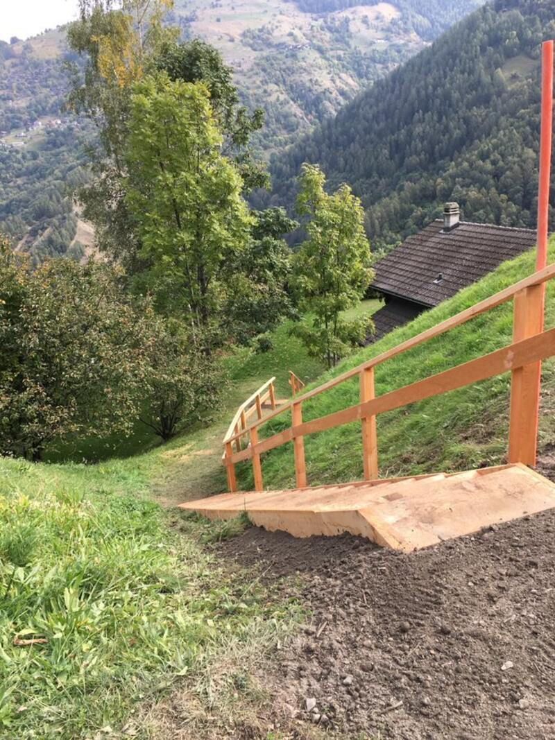 Une clôture en bois se trouve au sommet d'une colline herbeuse.
