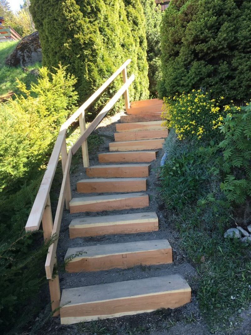 Un escalier avec une rampe en bois montant une colline.