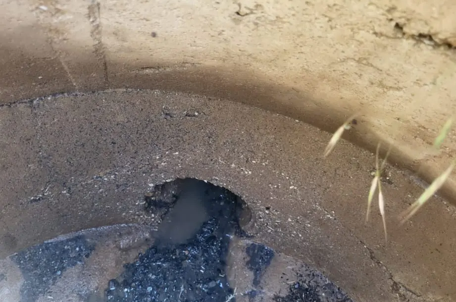 Un pozo o foso turbio, con agua oscura y paredes de piedra color beige